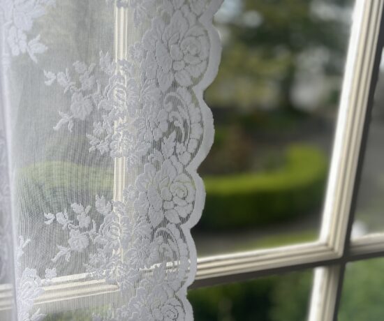 soft morning light through lace curtain on a quiet porch window